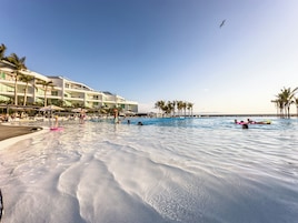 Una piscina al aire libre, sombrillas, tumbonas
