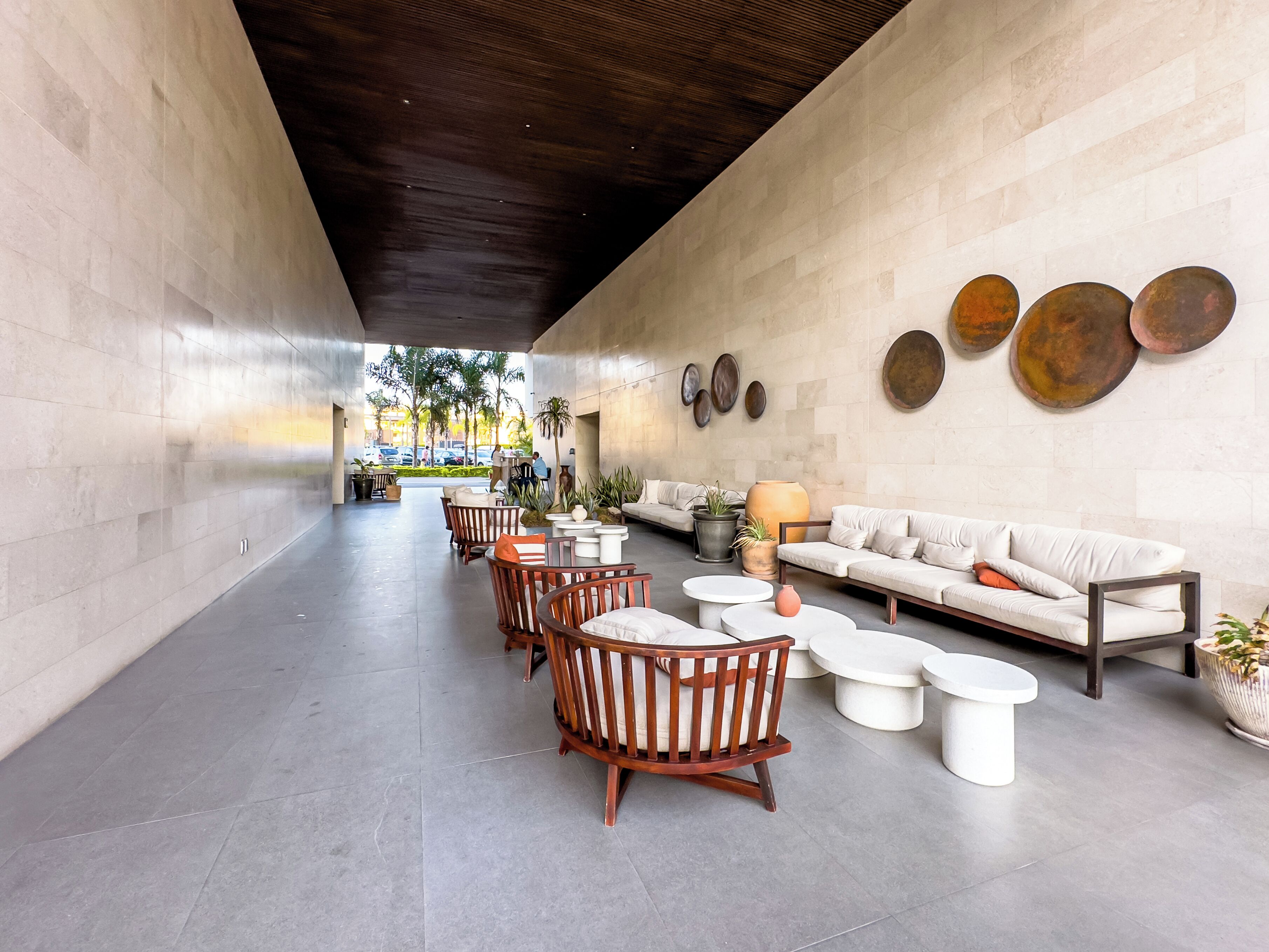 Een ruime lobby met een modern design, met een lange zithoek met banken en stoelen, een bijzettafeltje en decoratieve vazen.