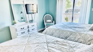 Un dormitorio con dos camas, un tocador, una silla y un televisor.