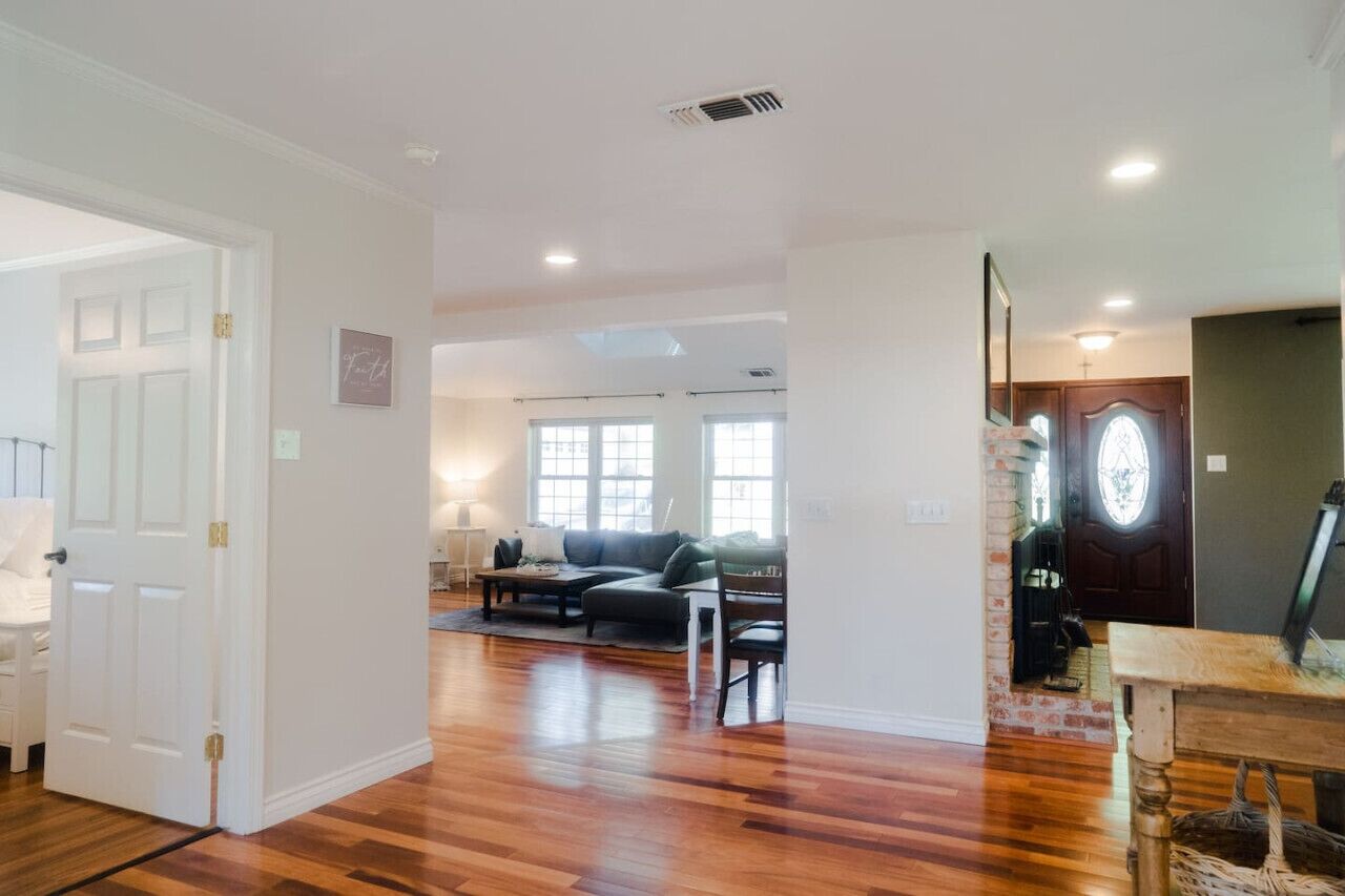 A spacious living room with hardwood floors, a sectional sofa, a coffee table, and a fireplace.