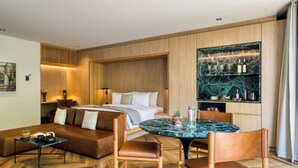 Une chambre d’hôtel moderne comprenant un lit, un coin repas avec une table en marbre et une cuisine intégrée avec un dosseret en marbre.
