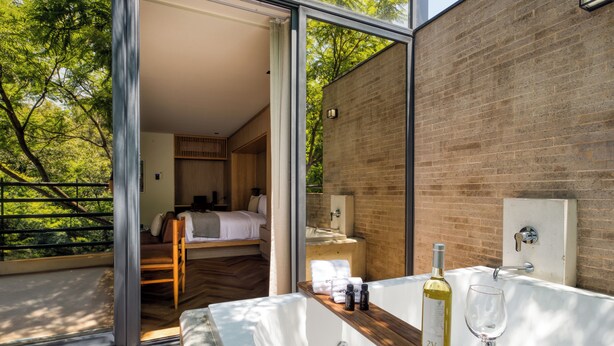 Une salle de bain moderne avec une grande baignoire, une bouteille de vin et un verre posés sur le comptoir.