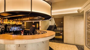 Un espace bar avec un comptoir incurvé, une variété de bouteilles et une personne qui travaille derrière le bar.