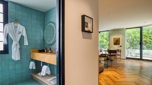 Une salle de bain moderne avec des carreaux de couleur turquoise, un meuble-lavabo en bois et un peignoir suspendu à un porte-serviettes.