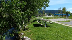 Ein Park mit Picknicktischen, einem Spielplatz und einem Fluss.