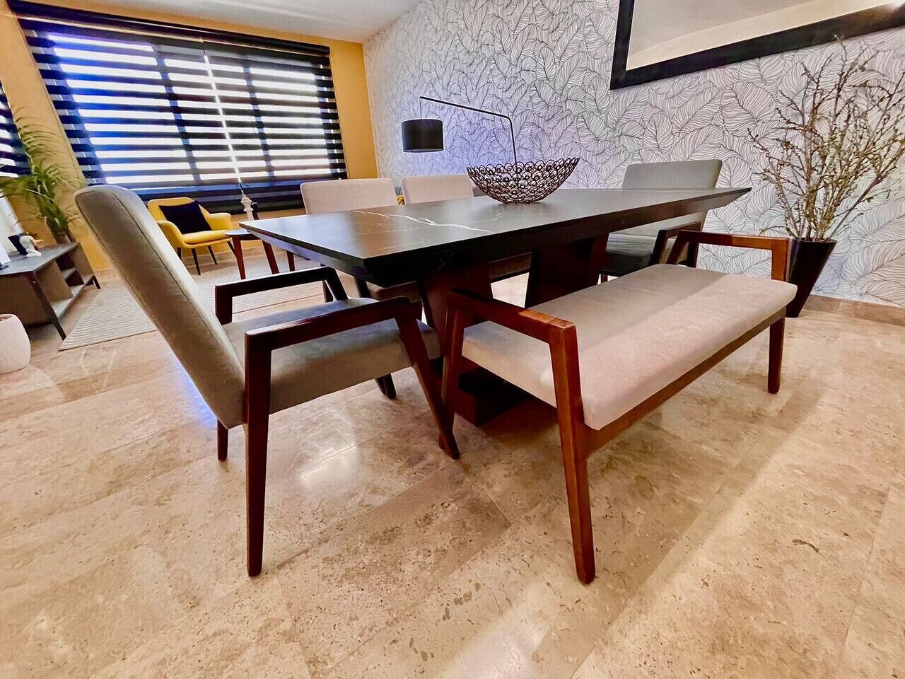 A dining area with a dark wooden table, cushioned chairs, and a decorative bowl centerpiece.