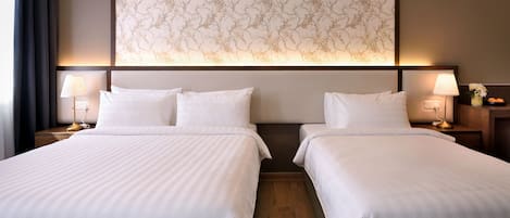 A hotel room with two beds, a large floral-patterned wall, and bedside lamps.