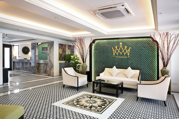 A lobby with a reception desk, a sofa, chairs, and a patterned floor. - The Leith (George Town)