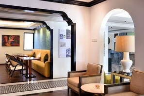 A hotel lobby with a sofa, chairs, a table, and an information board. - The Leith (George Town)