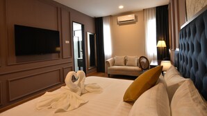 A hotel room with a large bed, a flat-screen TV, a sofa, and a lamp. - The Leith (George Town)