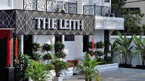 A multi-story hotel with balconies, a sign reading "THE LITE," and potted plants in the courtyard. - The Leith (George Town)