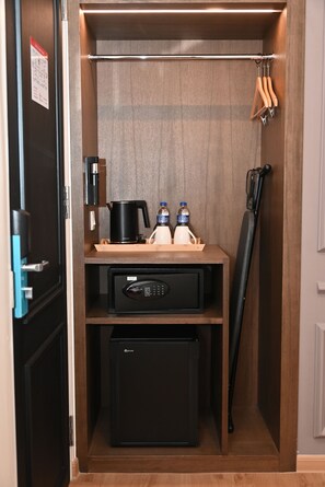 A compact kitchenette with a coffee maker, two bottles, a microwave, and a small refrigerator. - The Leith (George Town)