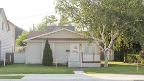 Einbungalow mit einer Garage, einem kleinen Vorgarten und einem Baum.
