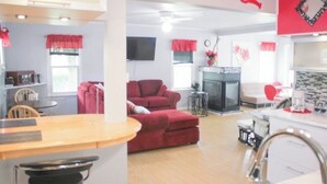 Ein Wohnzimmer mit rotem Sofa, Kamin und Küchenzeile mit Theke.