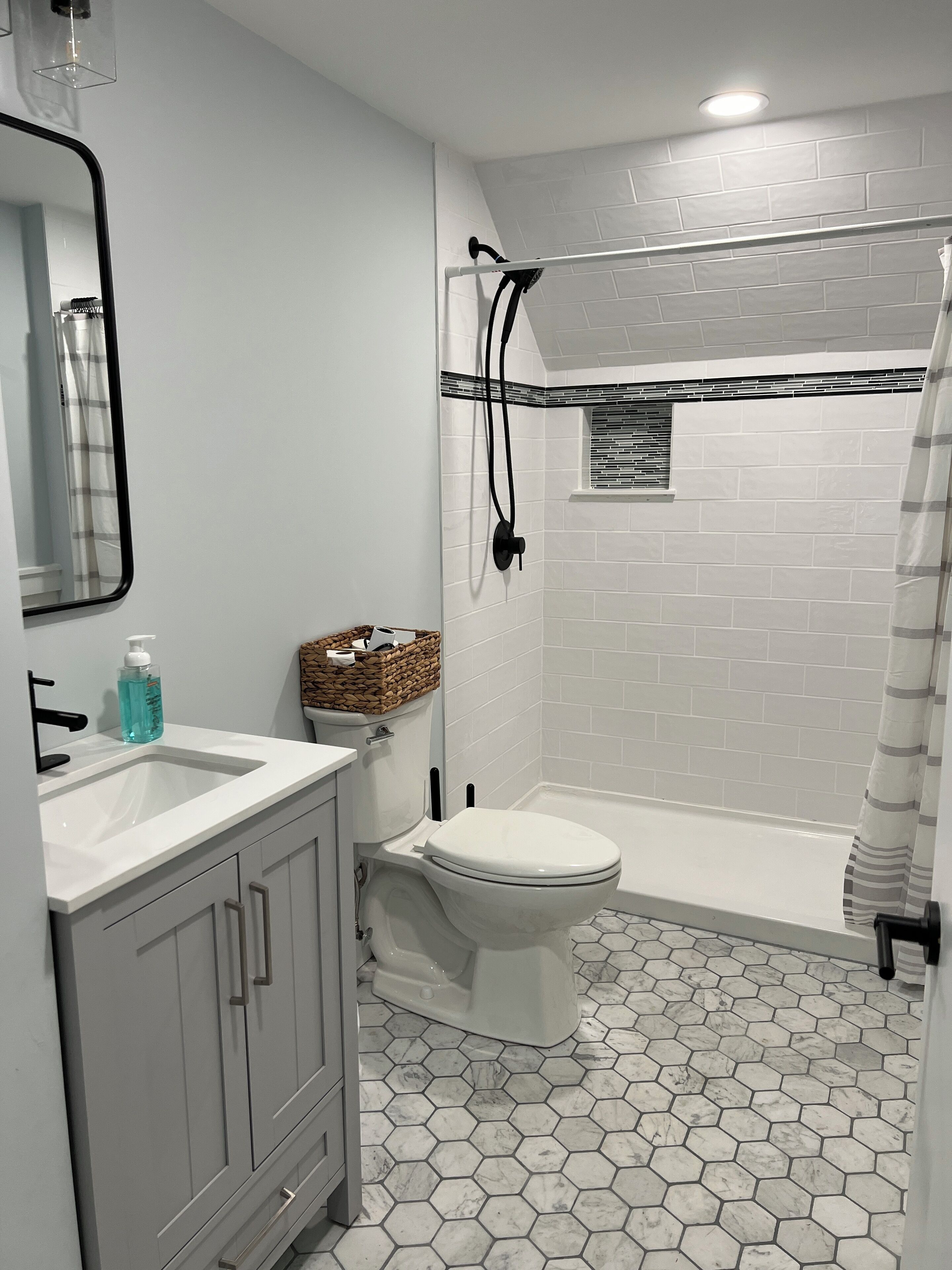 A bathroom with a white toilet, a sink with a mirror, and a shower area.