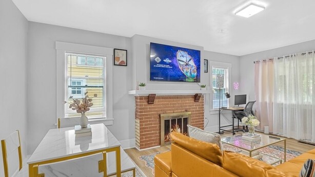 A modern living room with a fireplace, a TV mounted above it, and a sofa. - Spacious 5BedRooms House Near Millikin Univ – Perfect for Groups & Families! (Decatur)