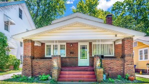 A two-story house with a front porch, brick exterior, and a green door. - Spacious 5BedRooms House Near Millikin Univ – Perfect for Groups & Families! (Decatur)