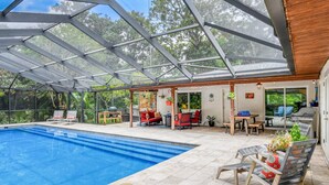 A covered outdoor swimming pool area with a glass roof, seating, and a barbecue setup. - Casa Contera (St. Augustine)