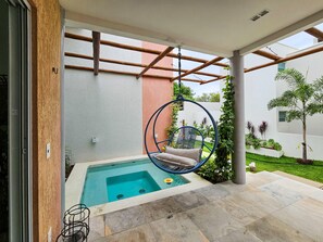 Un espace piscine extérieur moderne, doté d’un fauteuil suspendu, d’une petite piscine et d’une structure en forme de pergola.