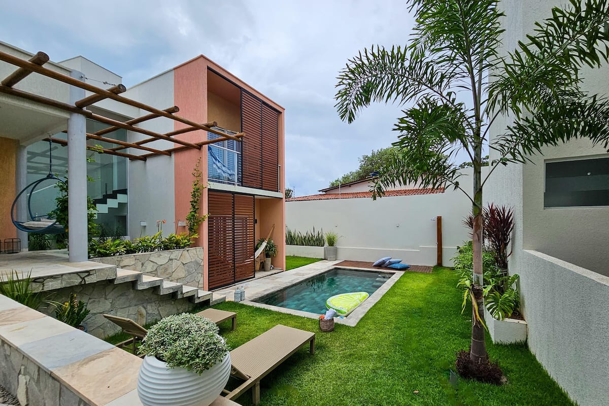 Ein modernes Haus mit Swimmingpool, einer Hängematte und einem kleinen Garten.