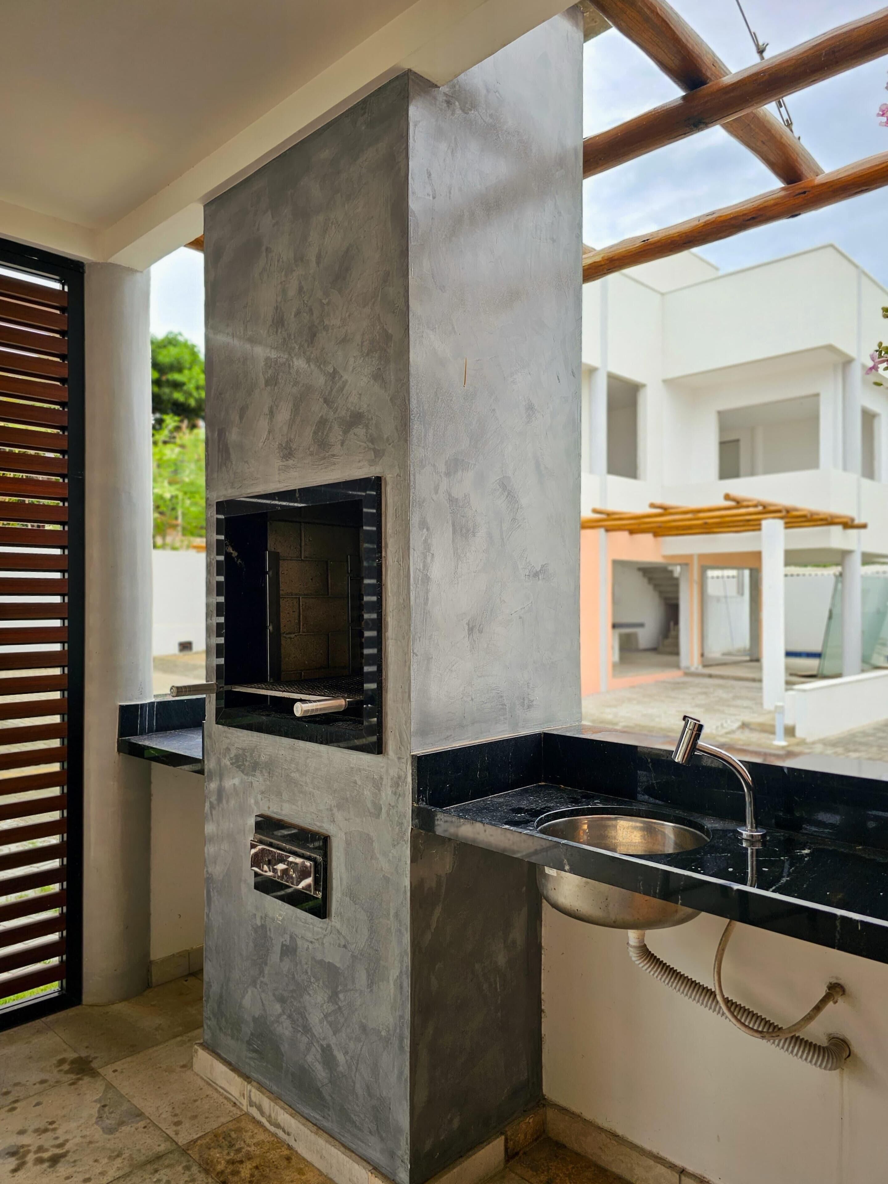 A kitchen with a built-in oven, a sink, and a window overlooking a white building.