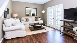 A living room with a sofa, a coffee table, a TV, and a large mirror. - Beautiful Townhouse Next to Disney Parks 24 (Kissimmee)