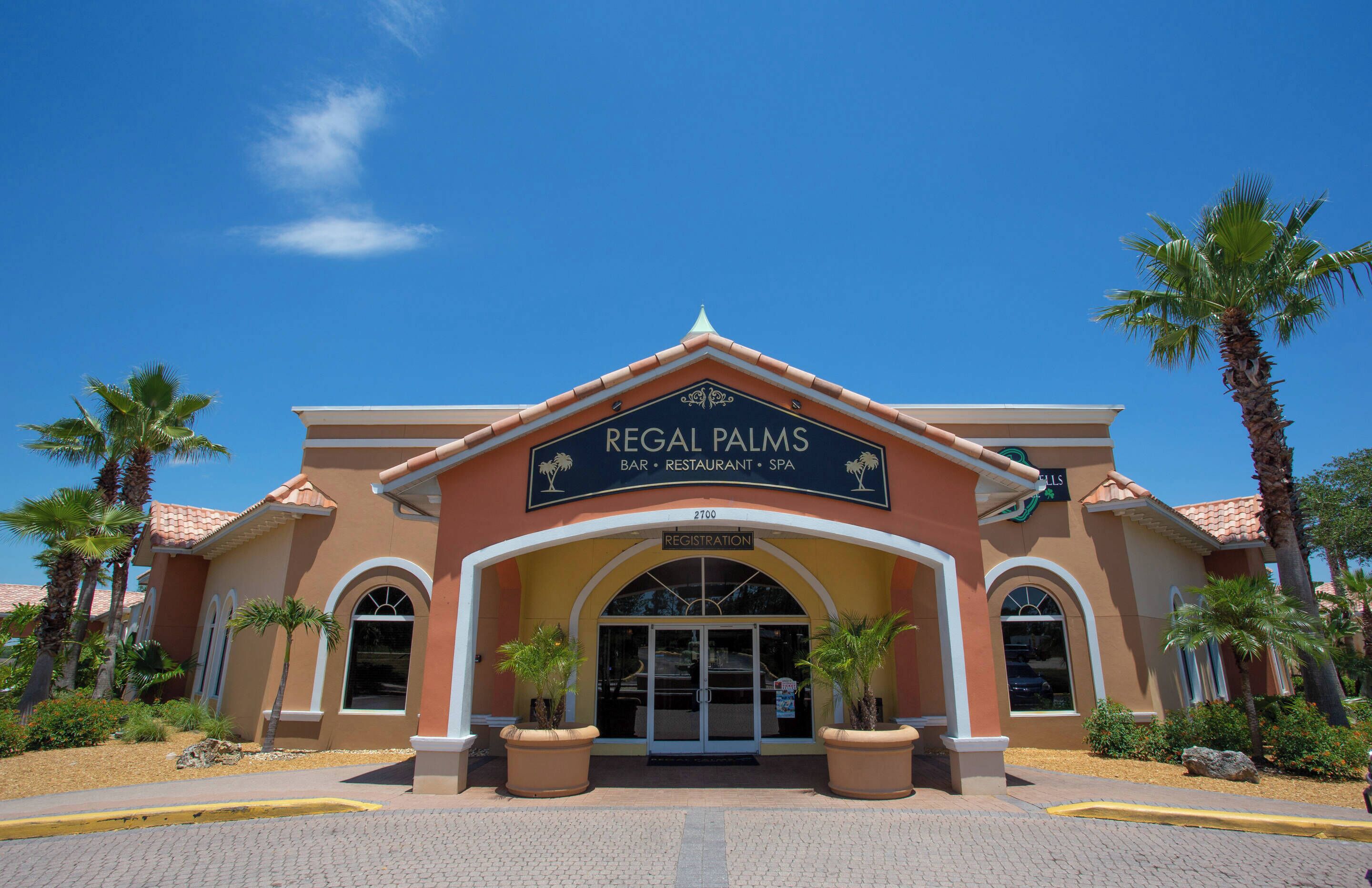 Een gebouw met een bord waarop staat 'Regal Palms Bar, Restaurant, Spa' en een receptie.
