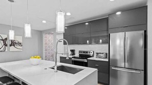 A modern kitchen with a central island, stainless steel appliances, and pendant lighting. - Beautiful Vacation Home With Splash Pool 35 (Kissimmee)