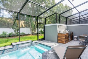 A covered outdoor swimming pool with a wooden deck and a barbecue area. - Free Pool Heat! Last Minute Deal! Near Disney 15 (Kissimmee)