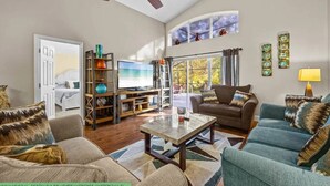 A spacious living room with a ceiling fan, a television, a sofa, and a coffee table. - Enchanting House few min Away From the Parks 52 (Kissimmee)