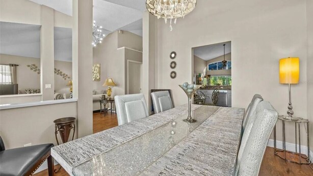 A dining area with a long table, chairs, and a chandelier. - Enchanting House few min Away From the Parks 52 (Kissimmee)