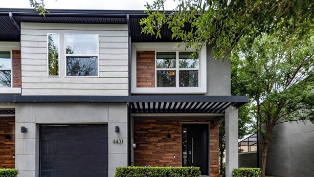 Une maison moderne à deux étages, dotée d’un garage, d’une entrée en briques et d’une pelouse bien entretenue.