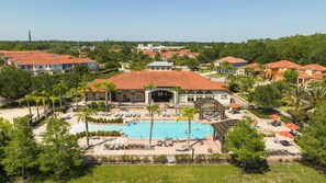 A resort with a central pool, multiple lounge areas, and a large building with a red-tiled roof.