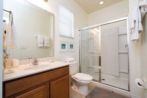 A modern bathroom with a glass-enclosed shower, a white toilet, and a vanity with a mirror.