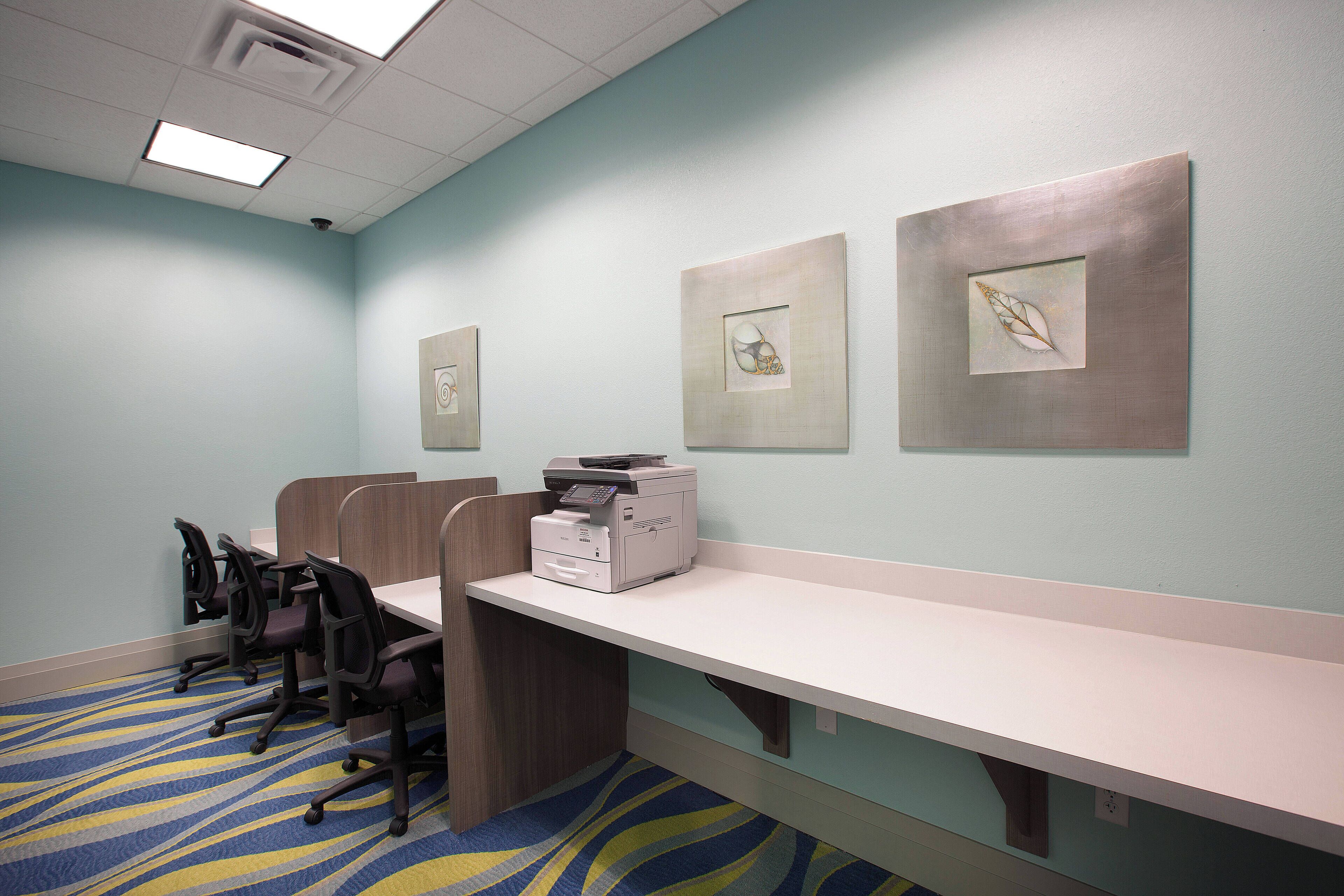 A conference room with a long table, four chairs, and a printer.