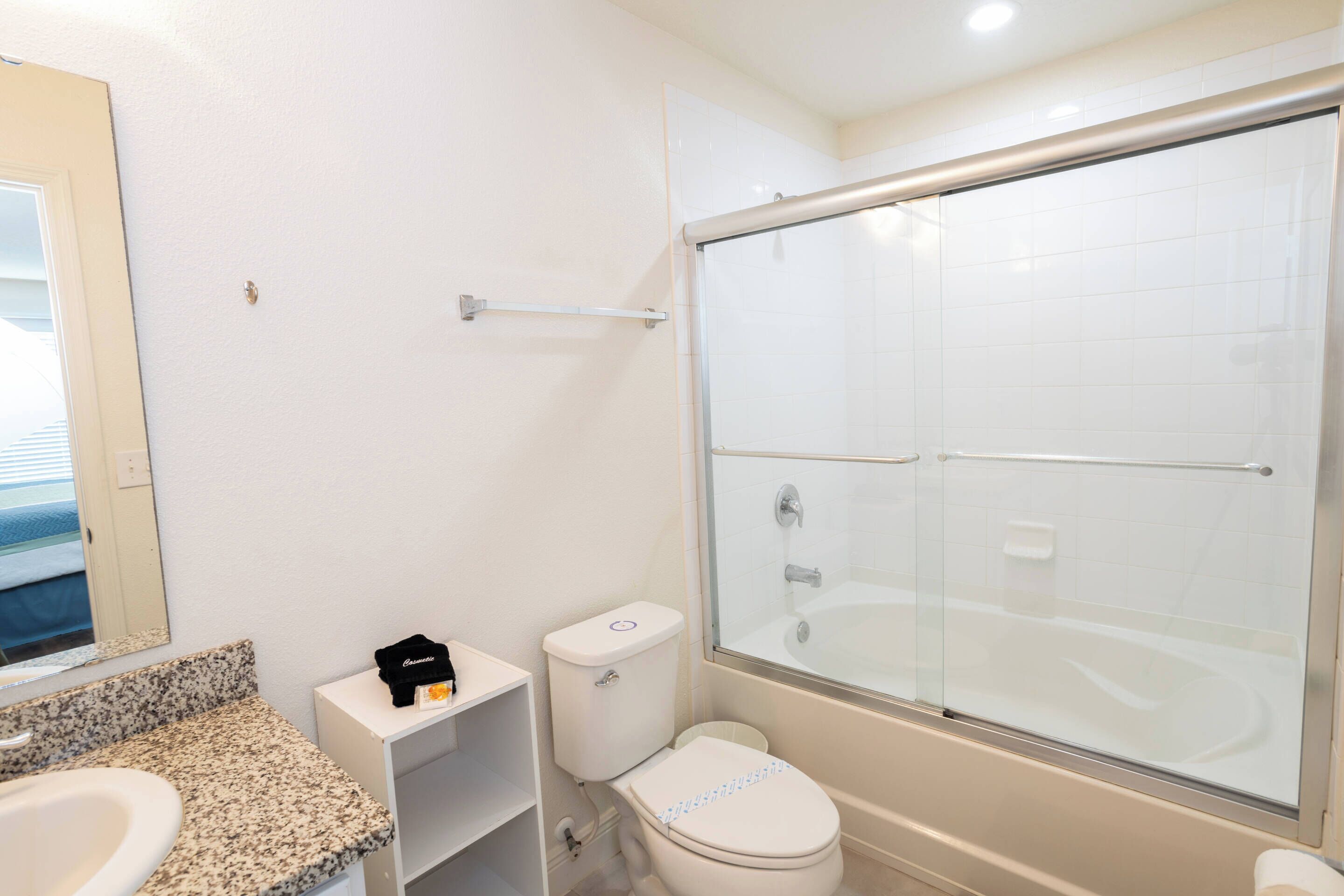 A bathroom with a white sink, toilet, and glass-enclosed shower.