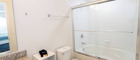 A bathroom with a white sink, toilet, and glass-enclosed shower.