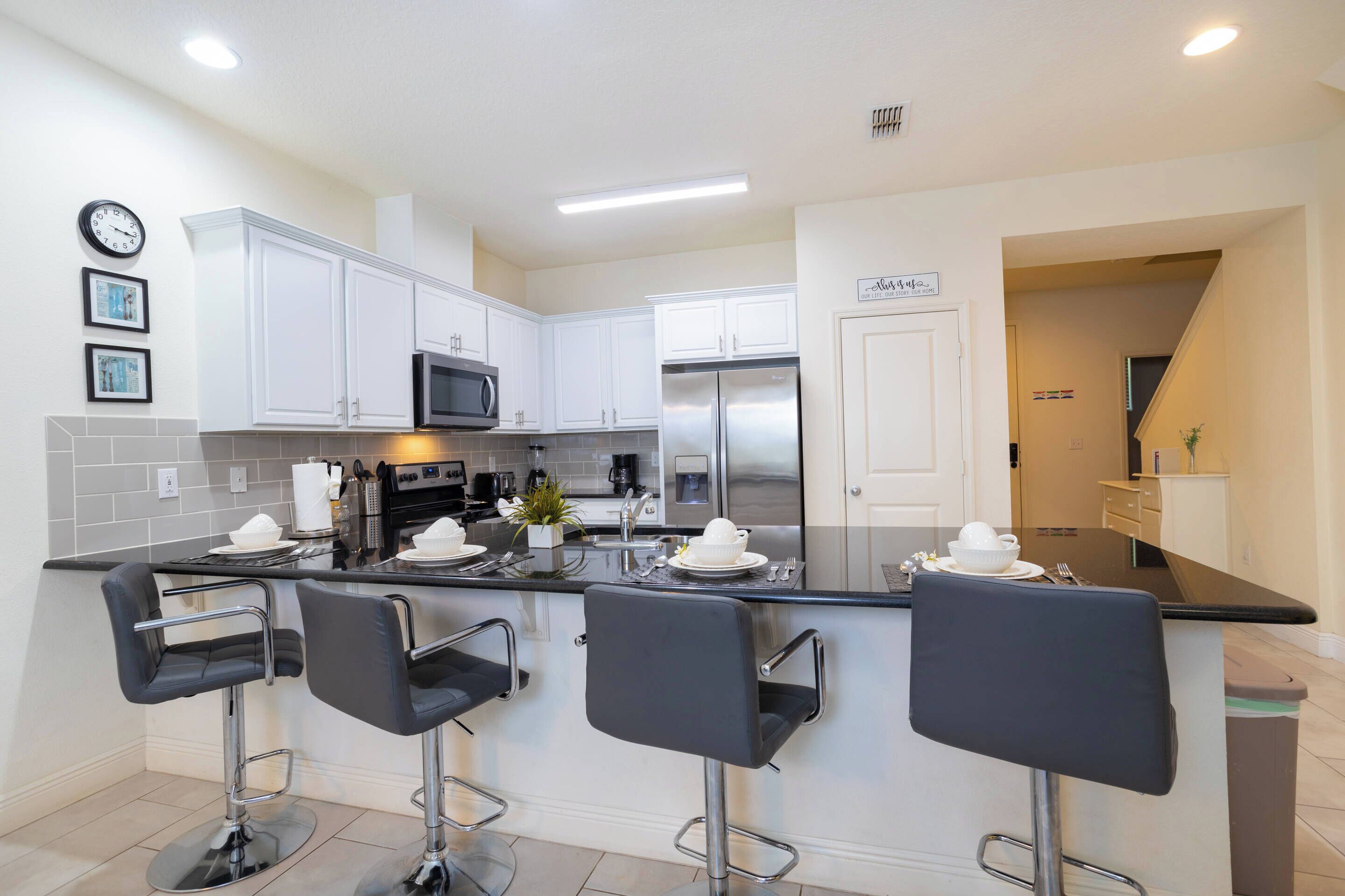 A modern kitchen with white cabinets, stainless steel appliances, and a central island with bar stools.