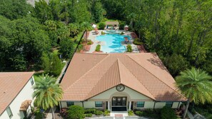 A resort with a swimming pool, surrounded by lush greenery and a tiled roof.