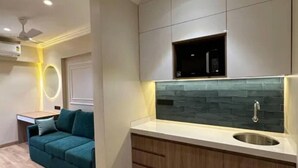 A modern kitchen with a stone backsplash, wooden cabinets, and a stainless steel sink. - Rudraya Homes (Mumbai)