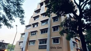 A multi-story building with a beige facade, multiple windows, and a sign reading "Shiv Om". - Rudraya Homes (Mumbai)