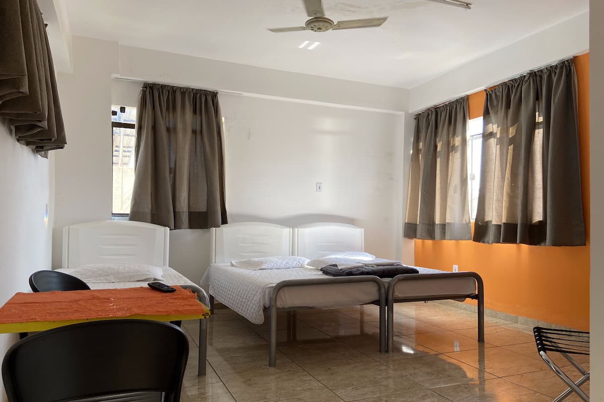 A room with two beds, a table, chairs, and a ceiling fan.