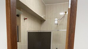 Un baño con inodoro, cabina de ducha y lavamanos.