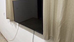 Un televisor de pantalla plana montado en la pared, con un cable de alimentación conectado a un enchufe.
