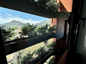 En balkon med udsigt over et bjerglandskab og en bygning i baggrunden.