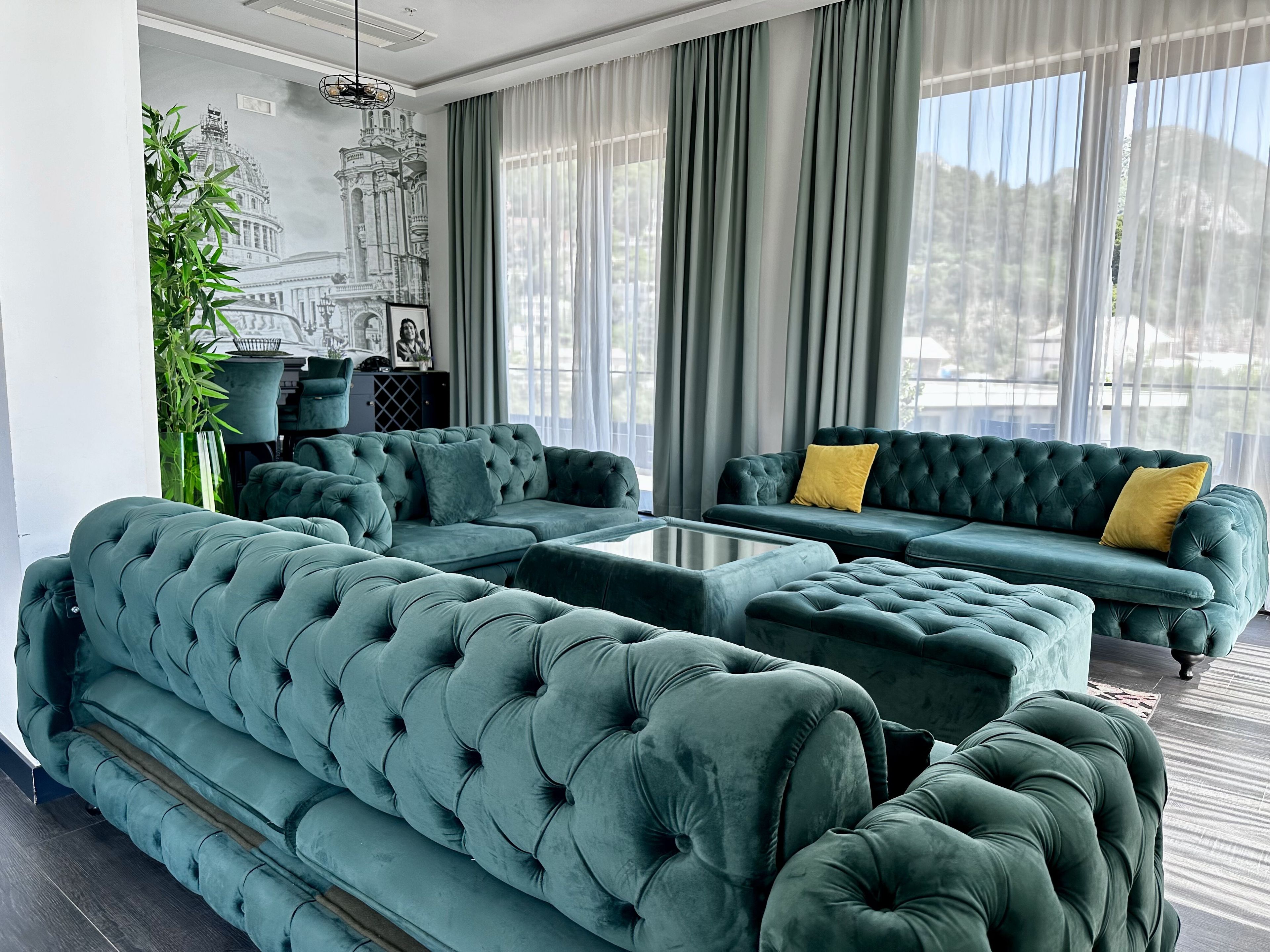A modern living room with a sectional sofa, a coffee table, and a view of a cityscape through large windows.