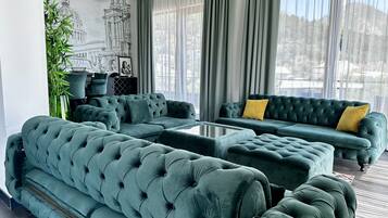 A modern living room with a sectional sofa, a coffee table, and a view of a cityscape through large windows.