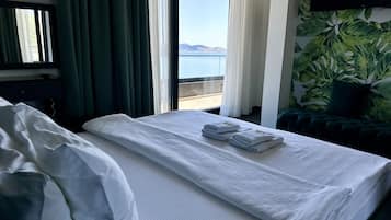 Habitación de hotel con cama, vista al mar y una pared cubierta de plantas verdes.
