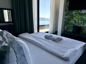 A hotel room with a bed, a view of the sea, and a green plant wall. - Hotel Del Medio (Sutomore)