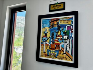 A framed artwork depicting a street scene with musicians and a sign reading "LA BODEGUITA DEL MEDIO" on the 5th floor. - Hotel Del Medio (Sutomore)